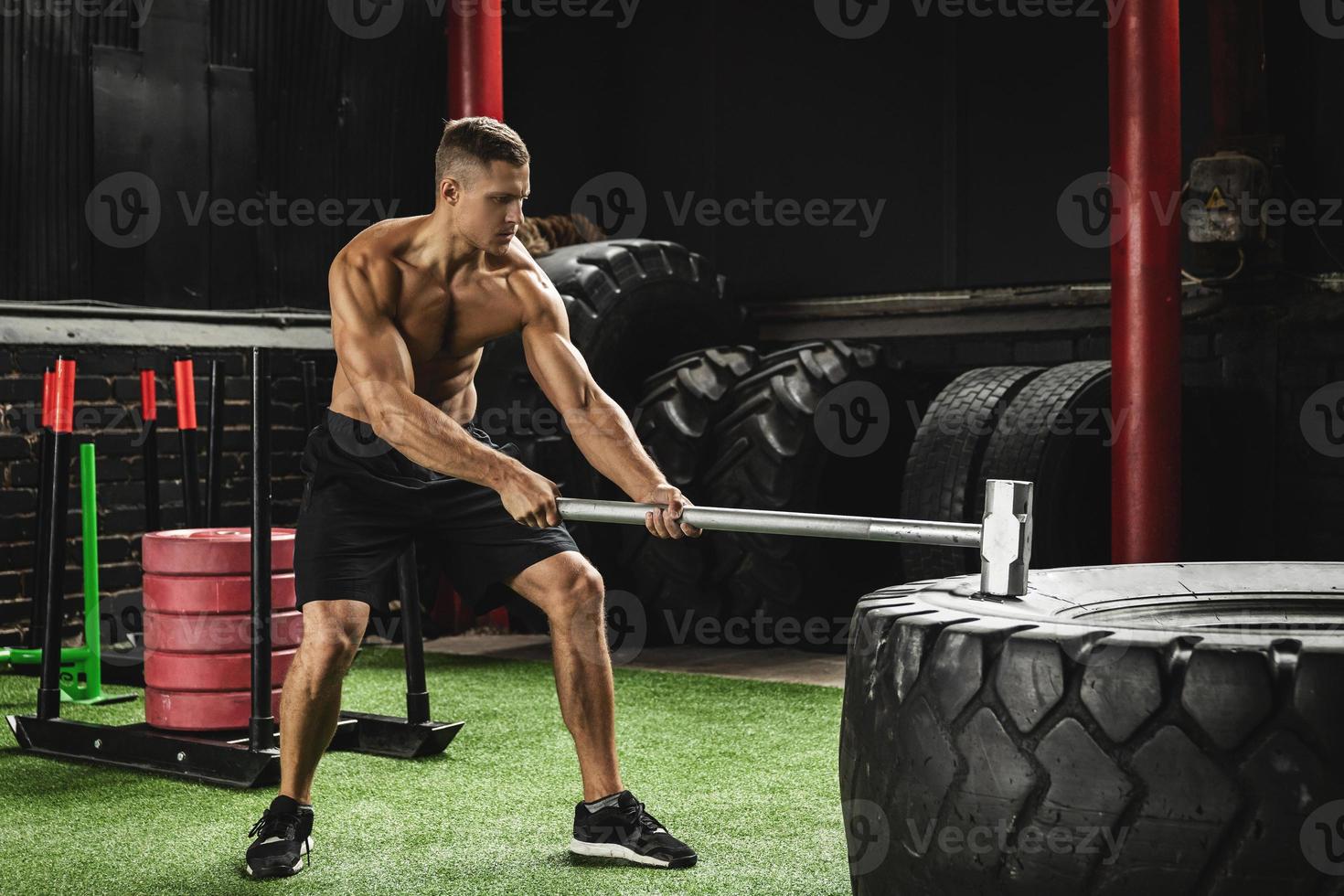 Man is hitting tire with a sledgehammer during his cross training