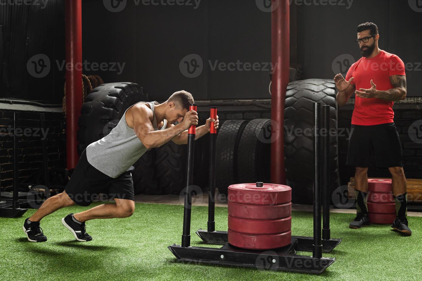 Strong sportsman during sled push exercise in the cross training gym