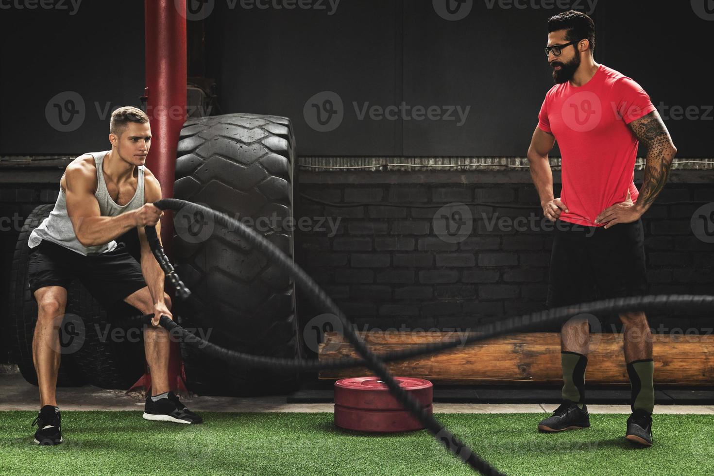 ejercicios de cuerda de batalla - joven deportista trabajando con su entrenador foto