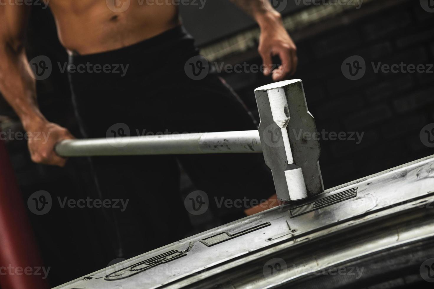 Man is hitting tire with a sledgehammer during his cross training