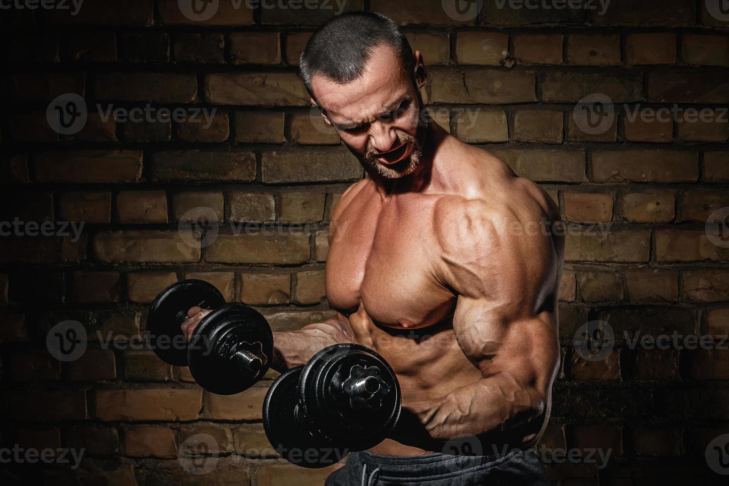 Bodybuilder doing exercises for biceps with a dumbbells photo