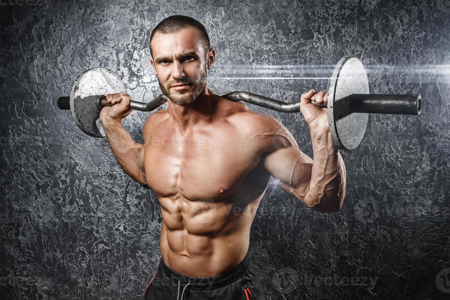Handsome muscular bodybuilder exercising with a barbell photo