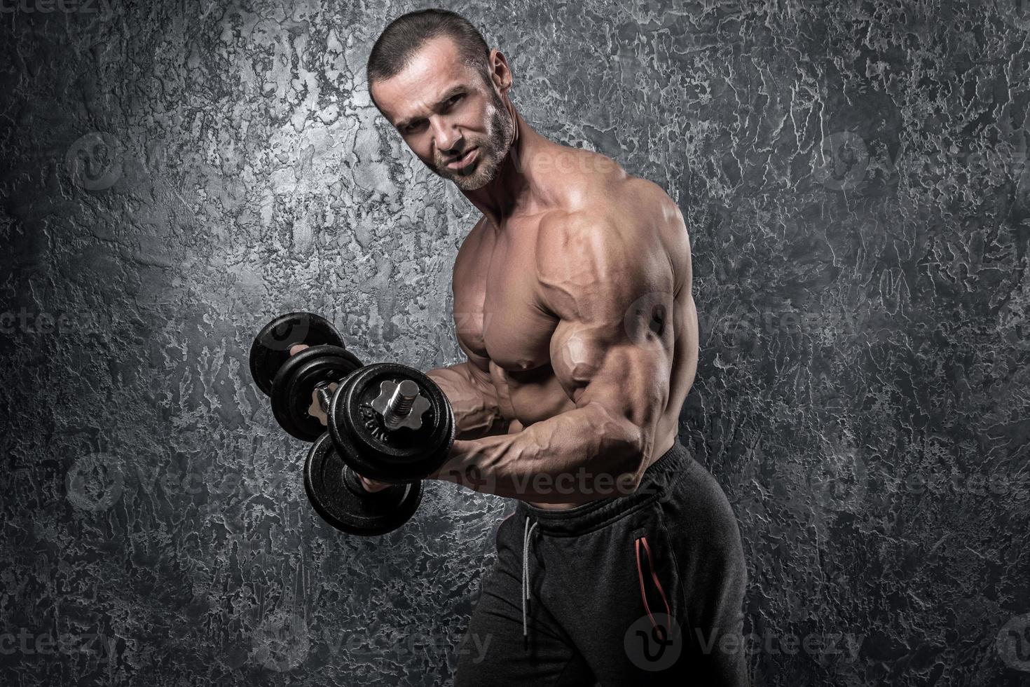 Bodybuilder man doing exercises with heavy dumbbells photo