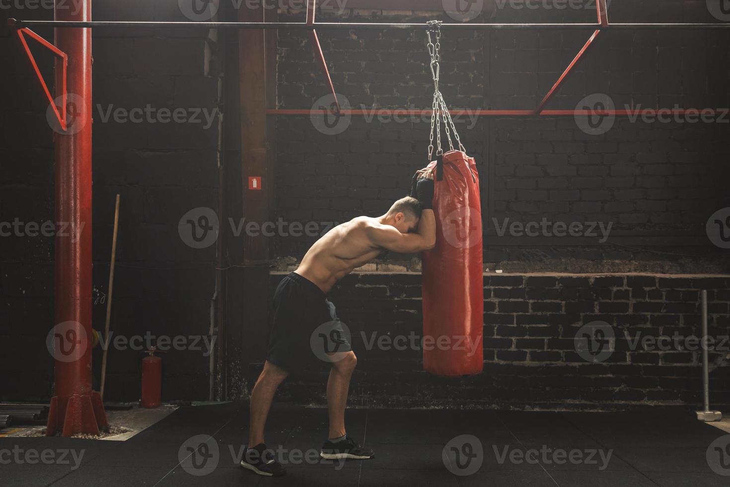 Fighter is very tired during his workout with a punching bag photo