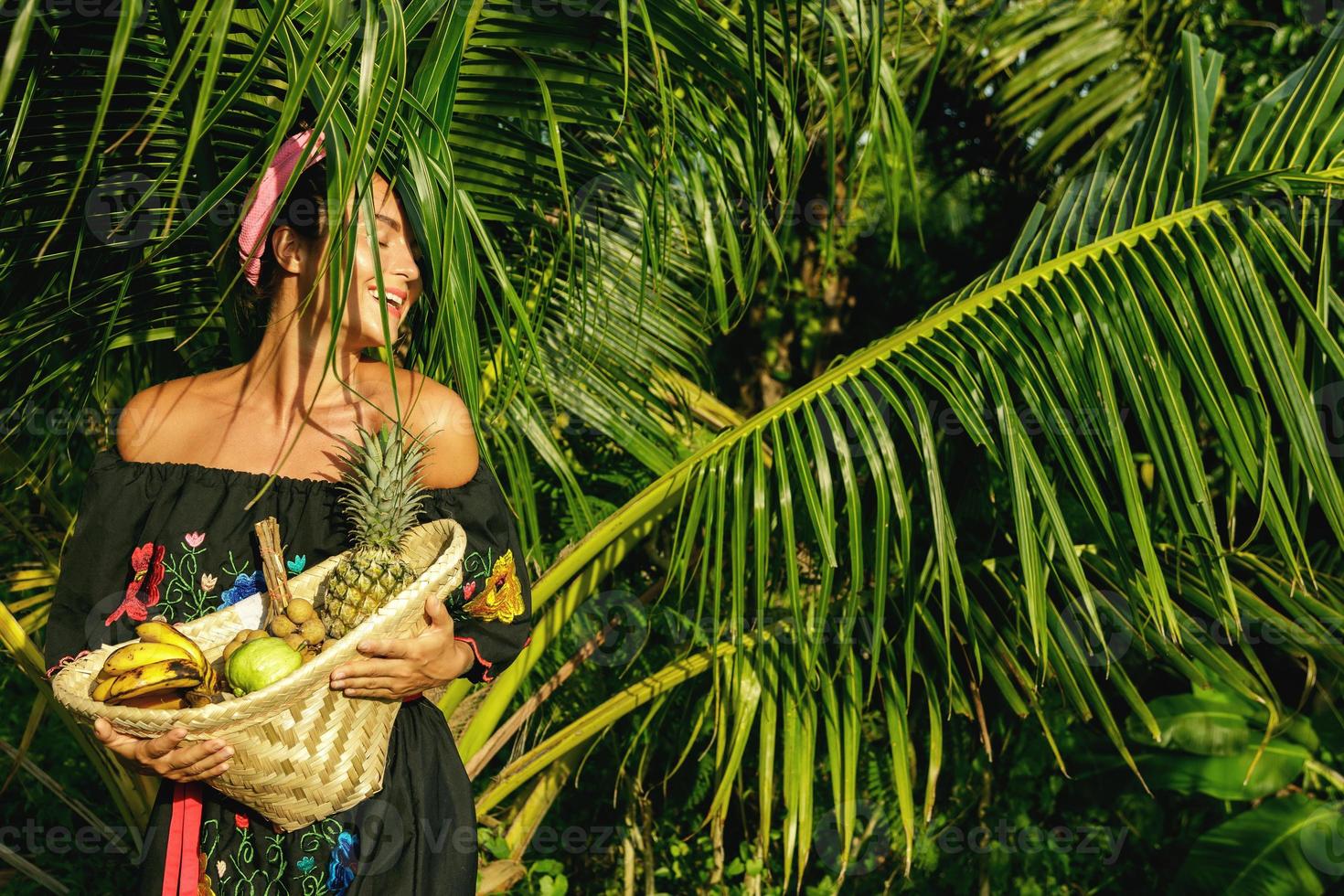 Happy young woman with a basket full of exotic fruits photo