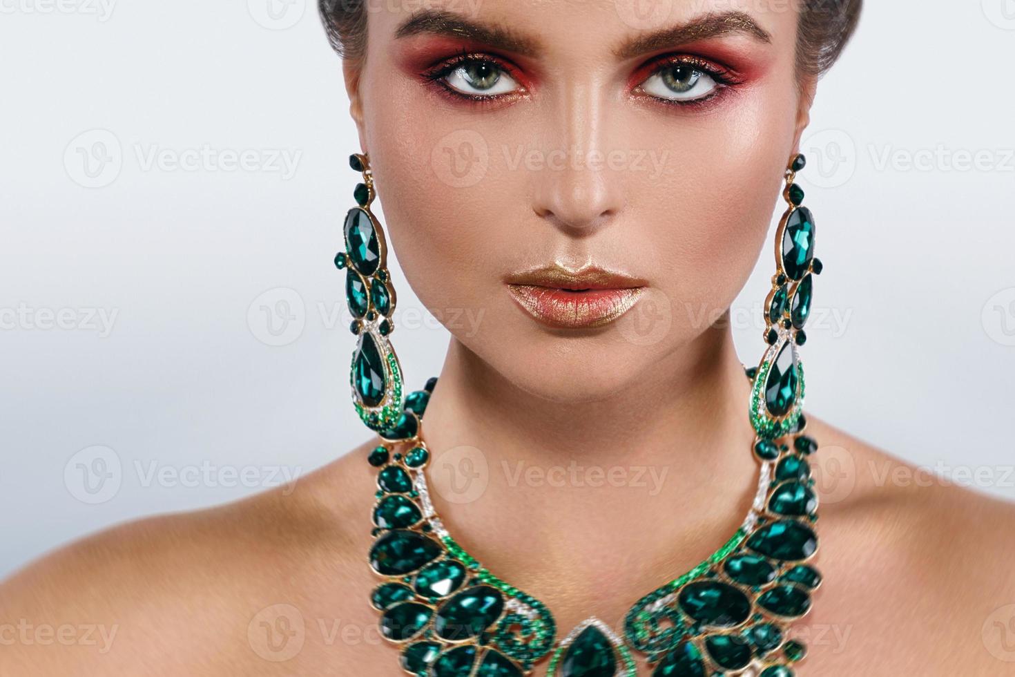 Sexy woman wearing big beautiful necklace and earrings with a lot of gems photo