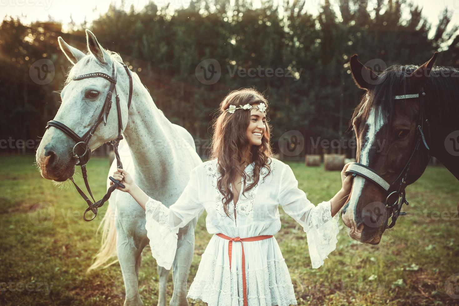 mujer joven en hermoso vestido blanco y sus hermosos caballos foto