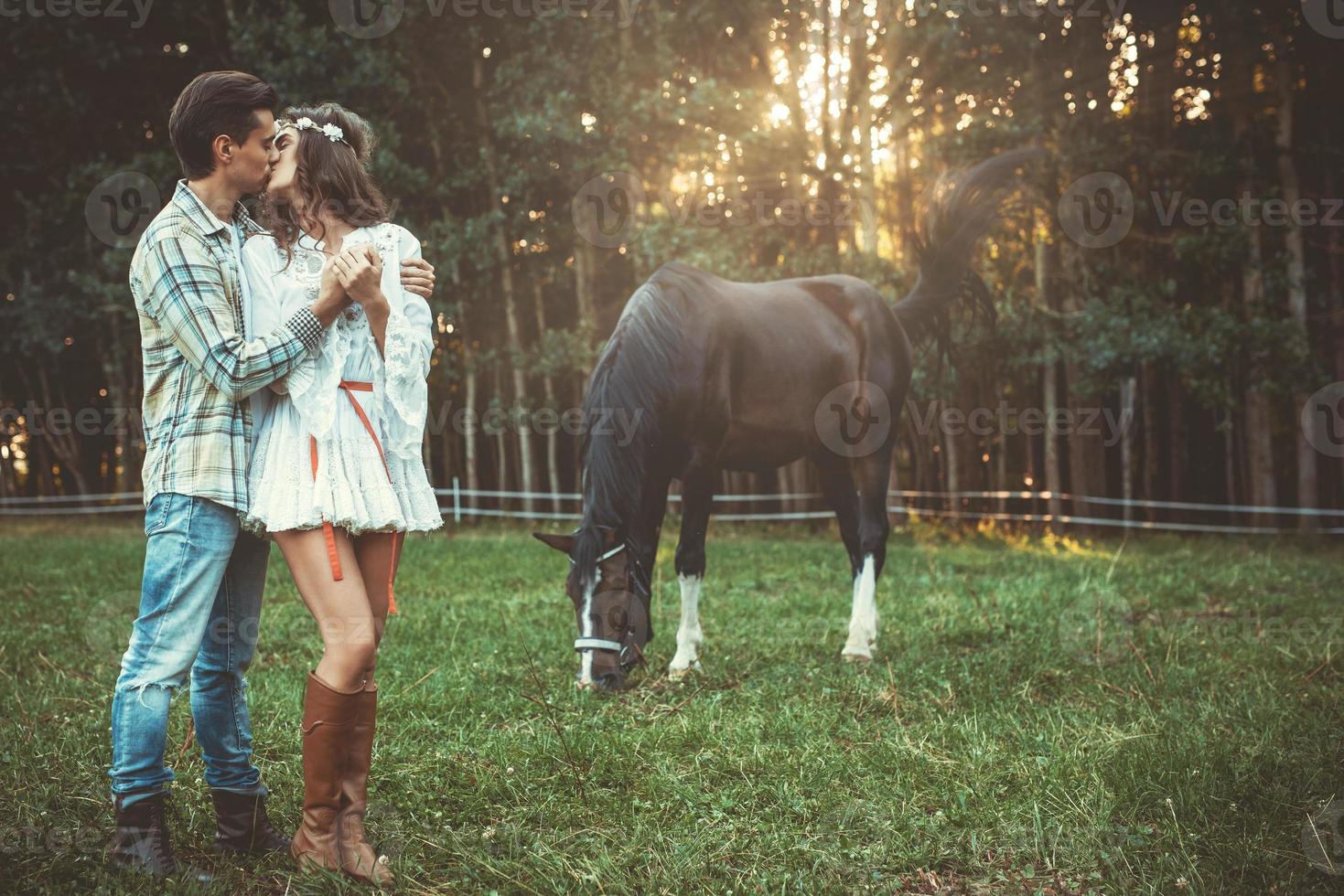 Young couple in embrace on the meadow with a horses photo