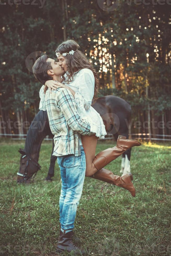 Young couple in embrace on the meadow with a horses photo