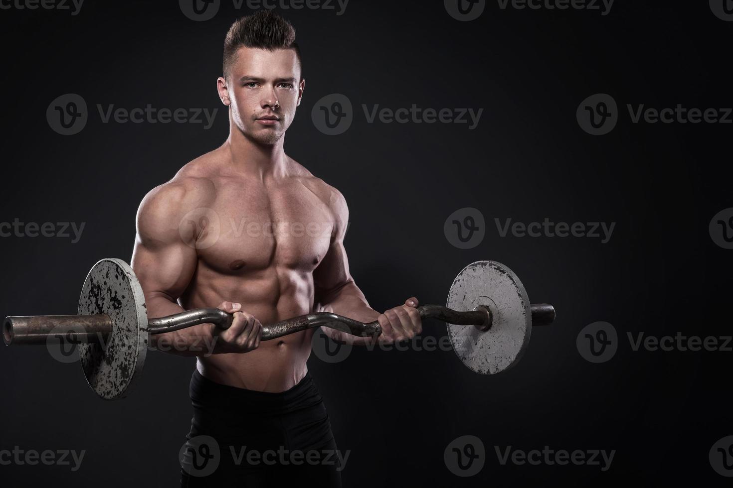 Young man bodybuilder with barbell in studio photo