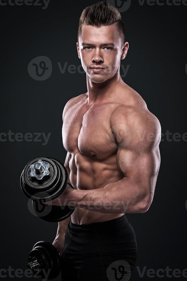 Young man bodybuilder doing exercises with dumbbells photo