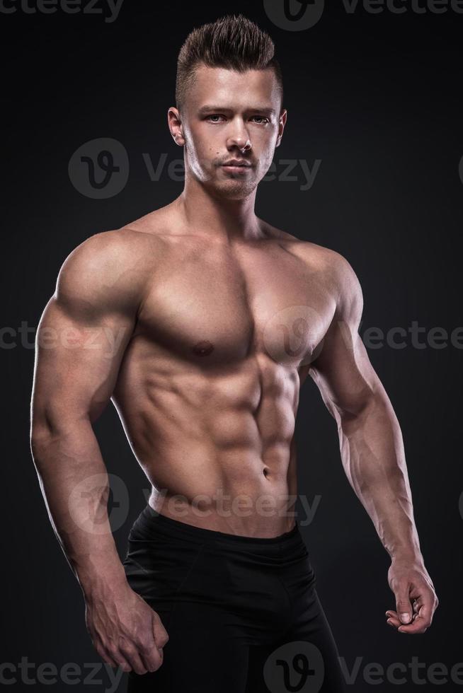 el joven culturista está mostrando sus músculos en el estudio foto