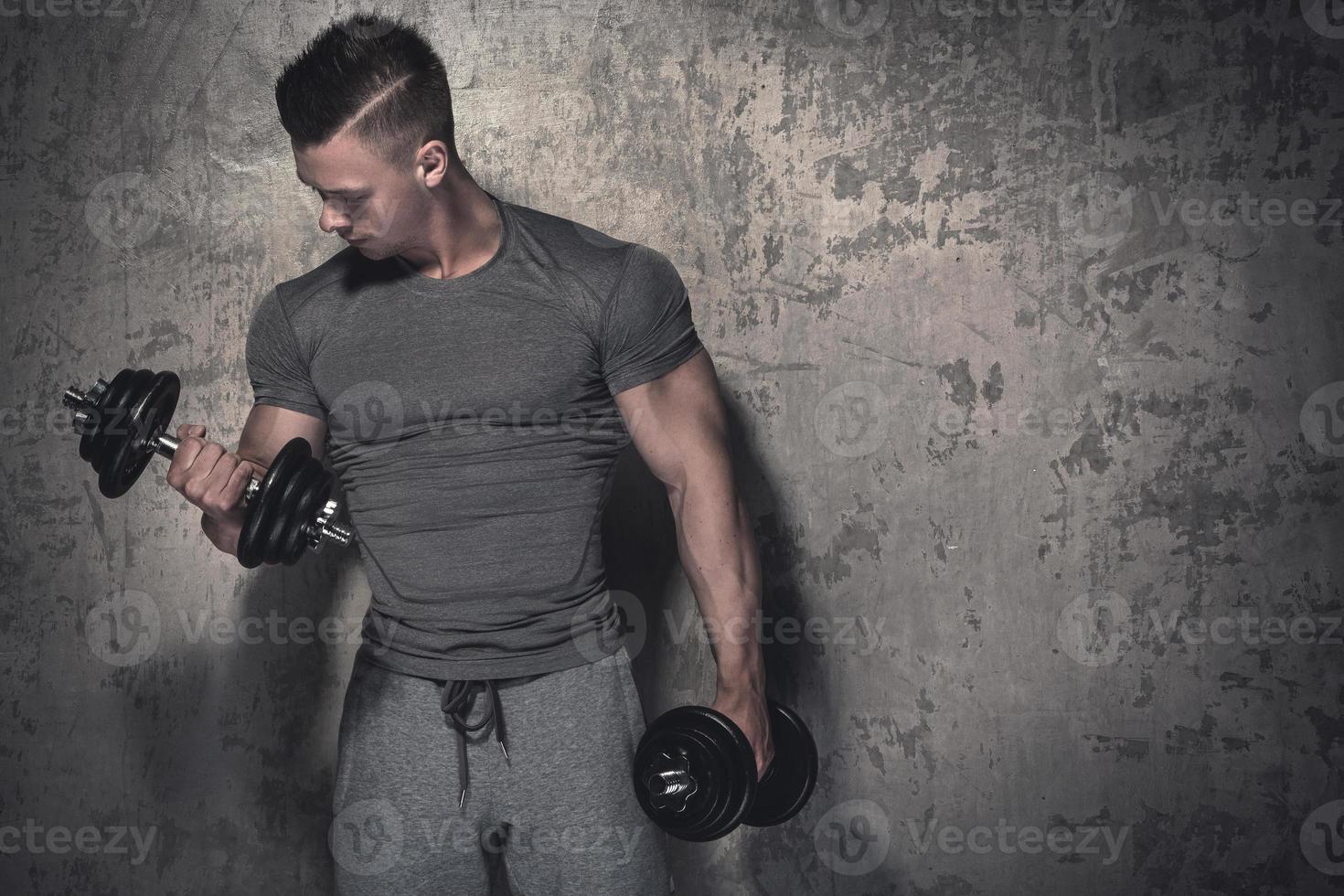 Young bodybuilder doing biceps curls with dumbbells photo