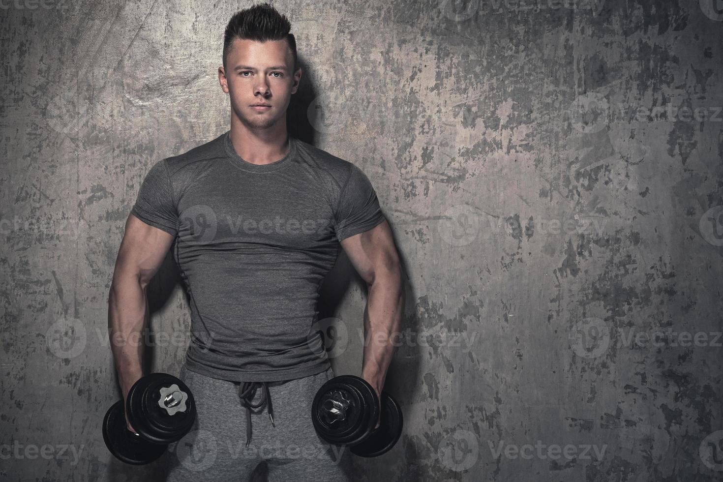 Young bodybuilder doing biceps curls with dumbbells photo