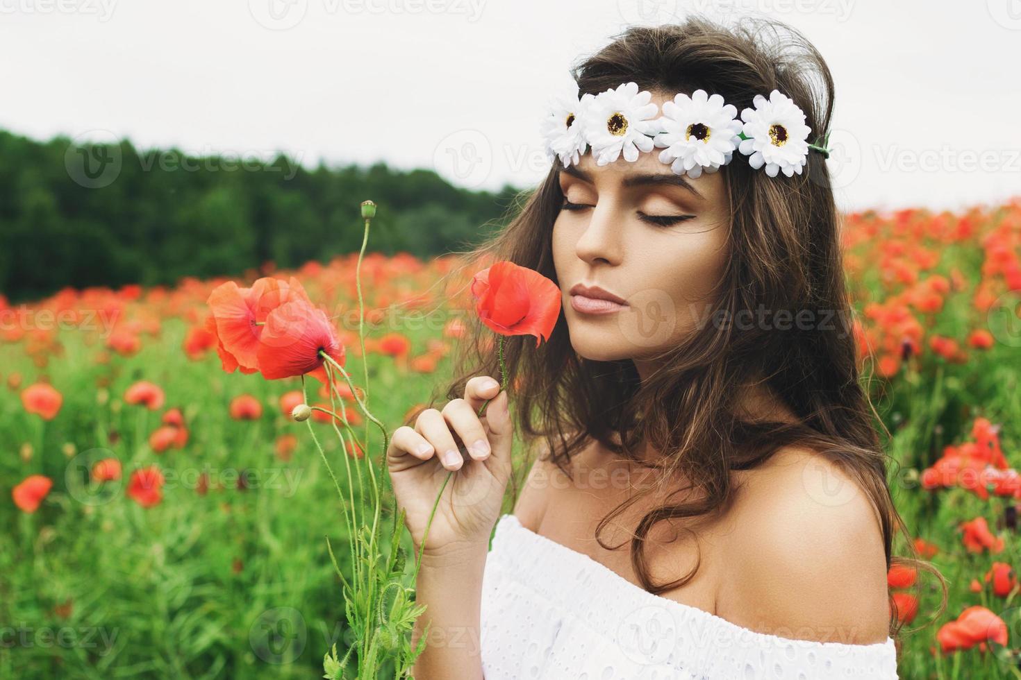 bella mujer en el campo con muchas flores de amapola foto