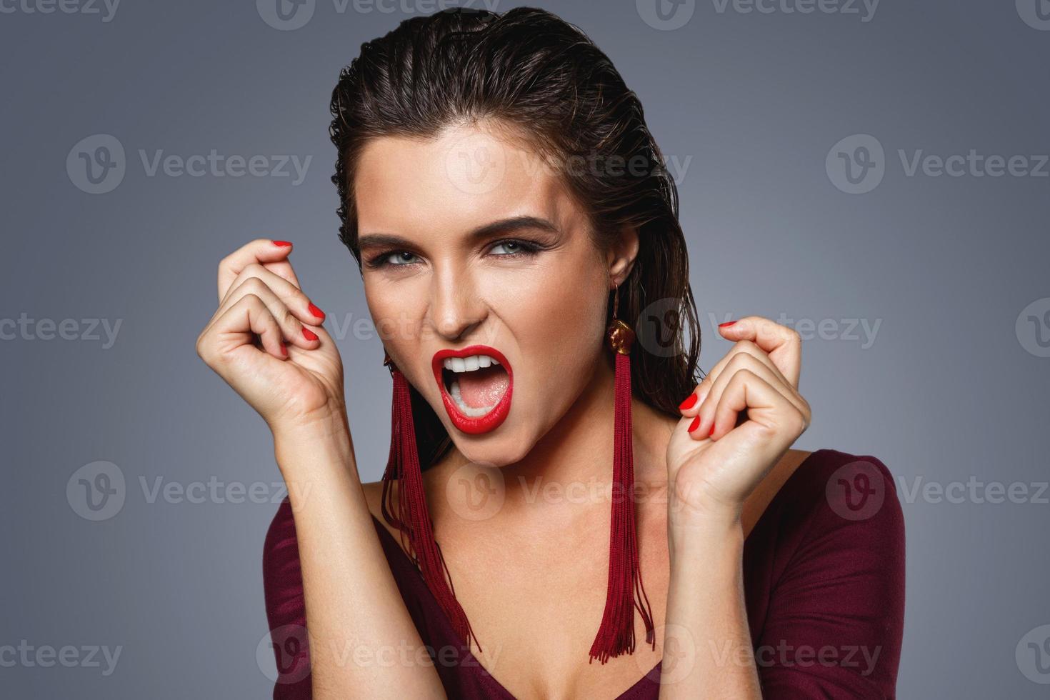 Stunning woman with a beautiful makeup wearing long red earrings photo