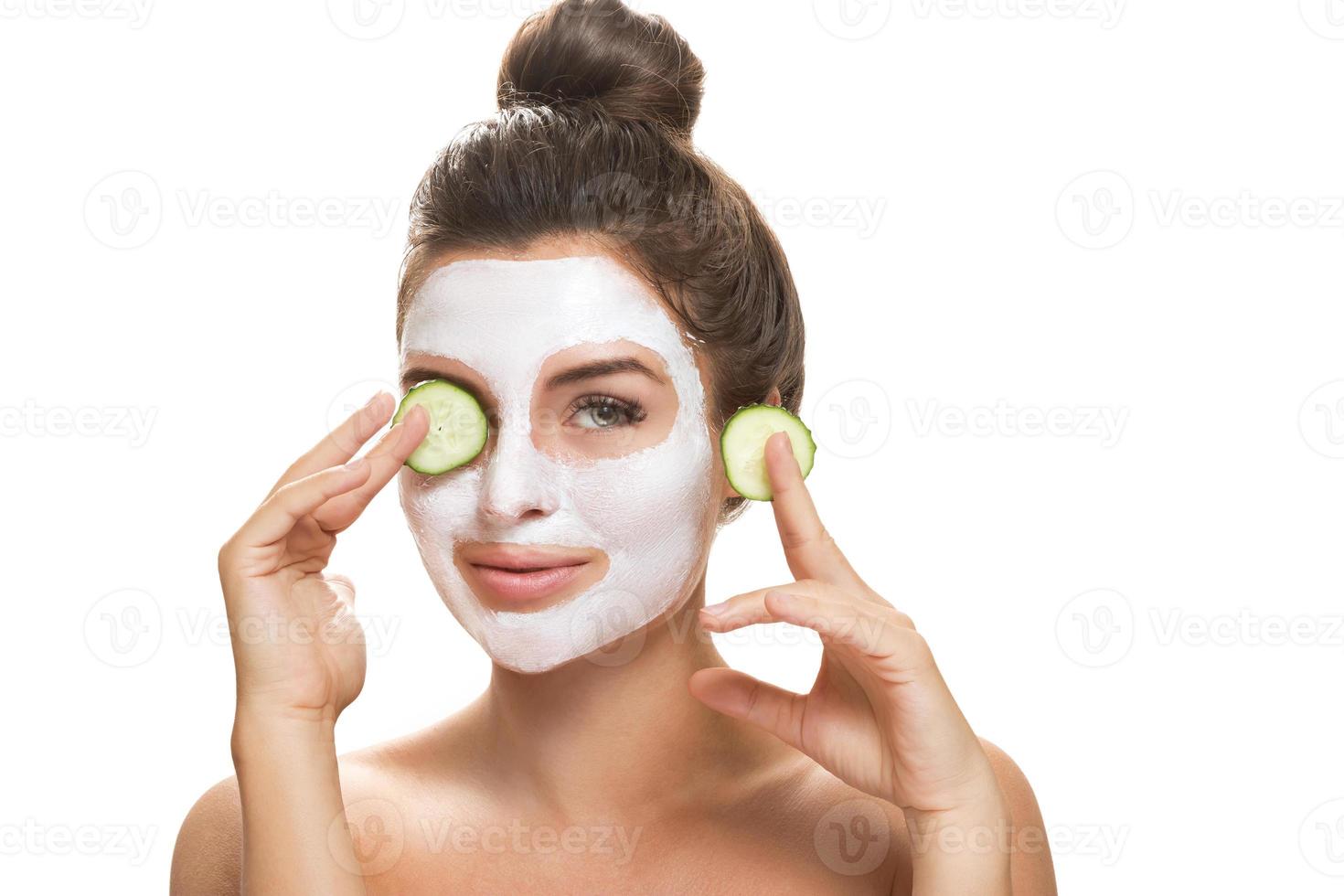 Woman with facial mask and cucumber slices in her hands photo