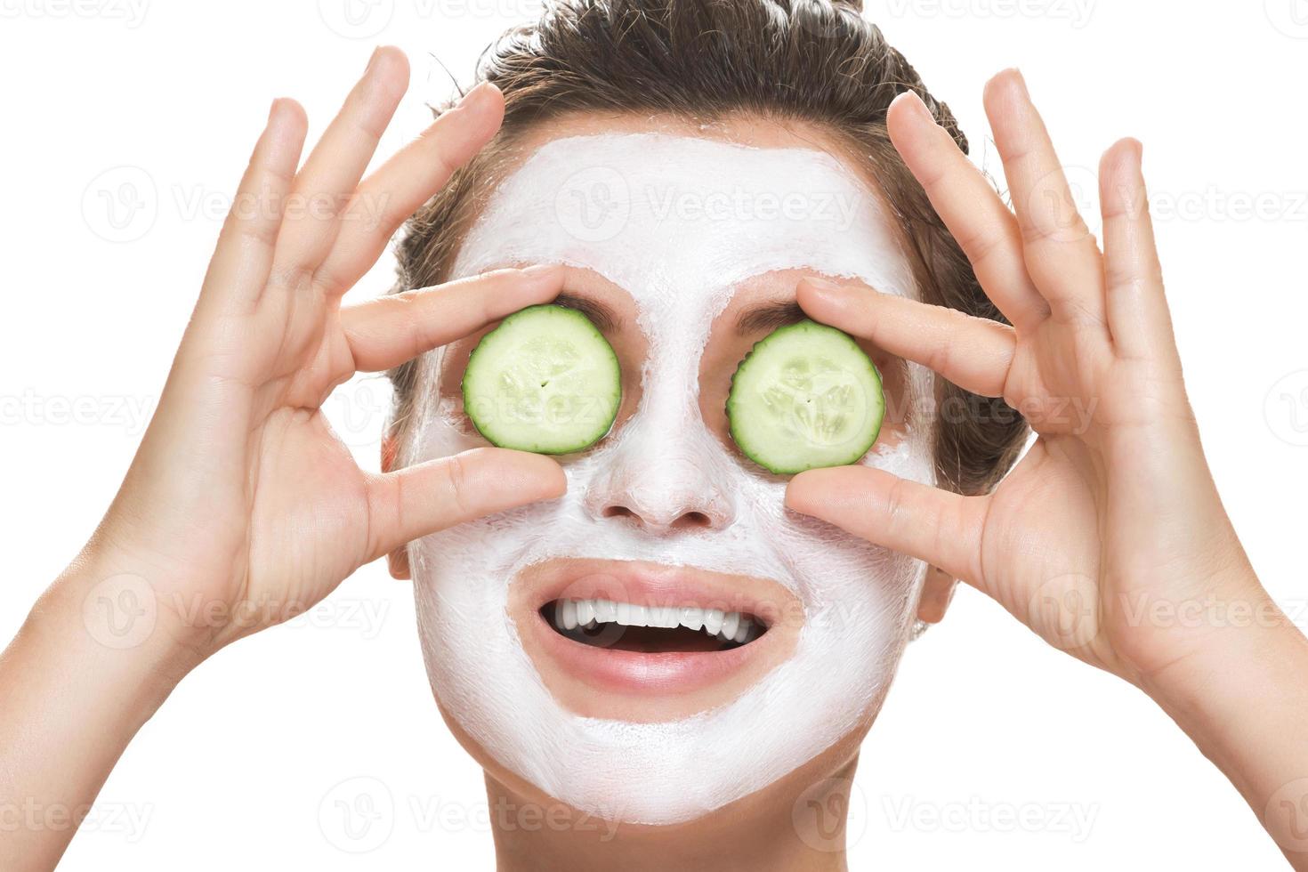 Woman with facial mask and cucumber slices in her hands photo