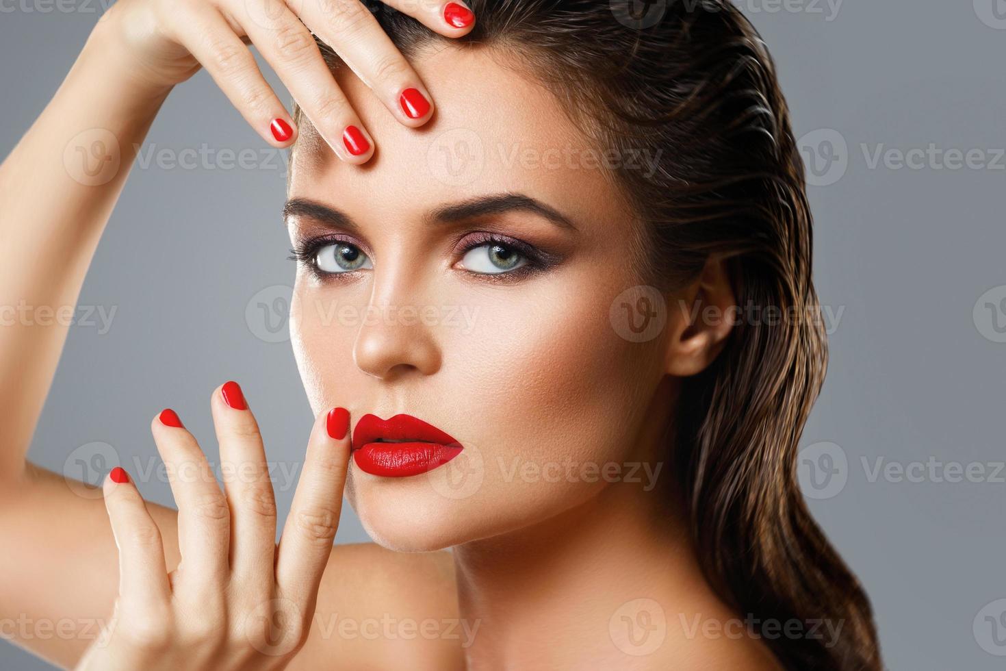 Portrait of beautiful young woman with a red lipstick and nail polish photo