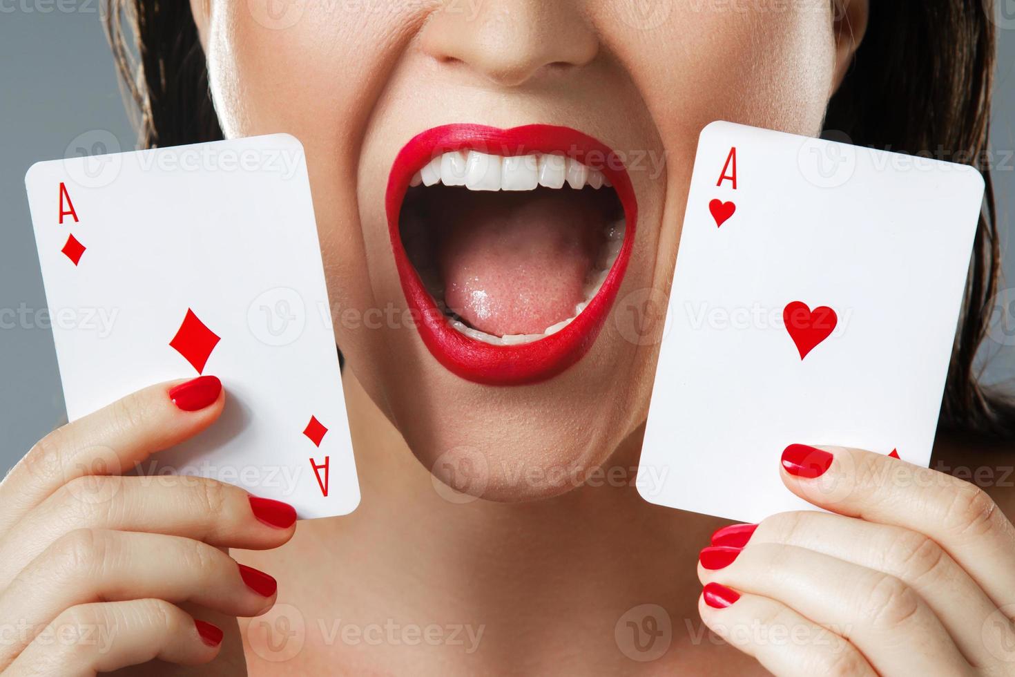 Woman with red lips is holding two aces. photo