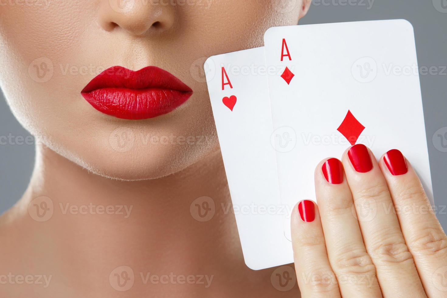 Woman with red lips is holding two aces. photo