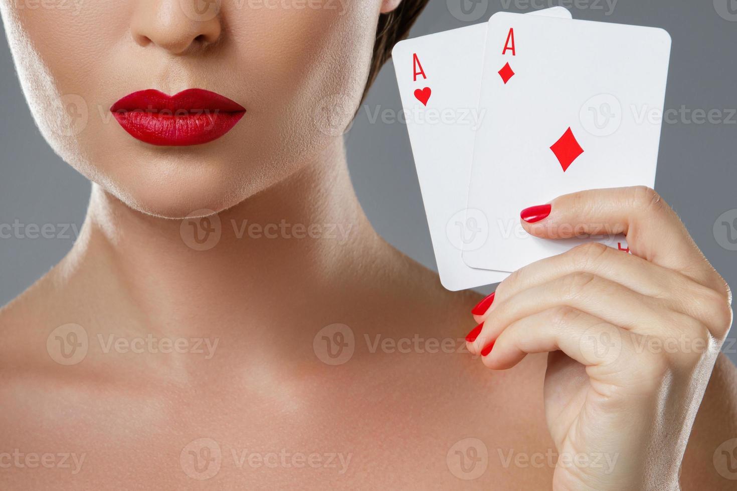 Woman with red lips is holding two aces. photo