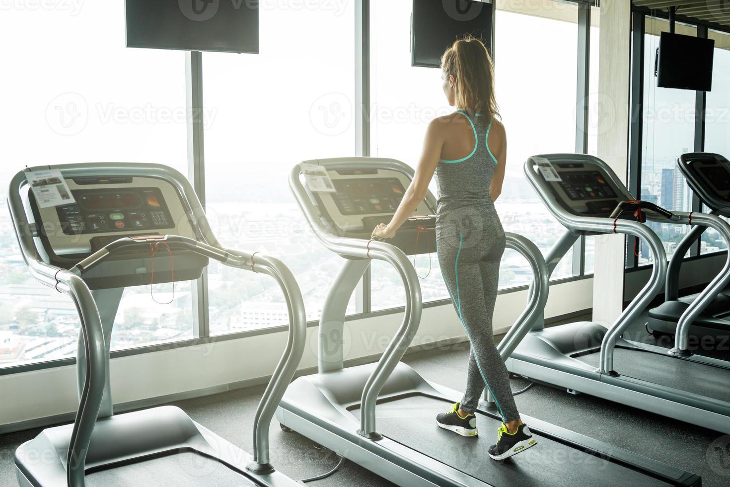Young and sporty woman on treadmill in gym photo