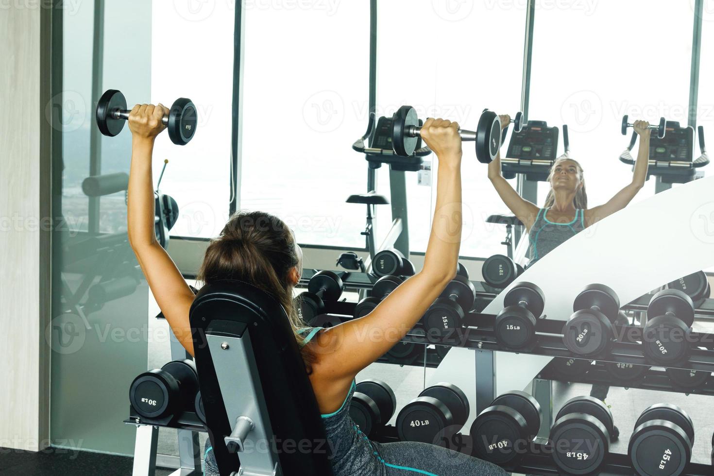 Woman working out with dumbbells in gym photo