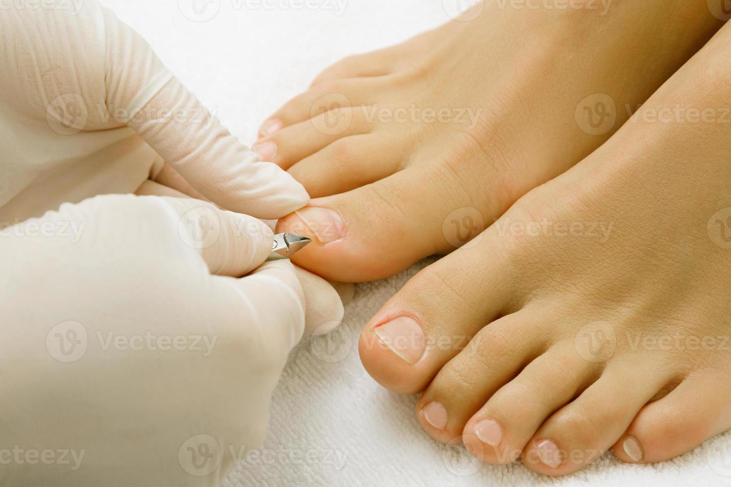 Pedicure master work. Close up of female nails and pedicurist hands in gloves with special tool. photo