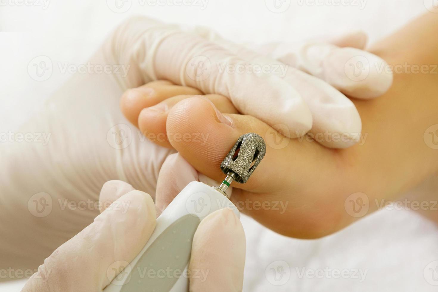 obra maestra de pedicura. primer plano de pies femeninos y manos en guantes con una máquina herramienta especial. foto