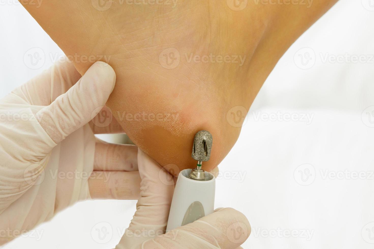 obra maestra de pedicura. primer plano de pies femeninos y manos en guantes con una máquina herramienta especial. foto