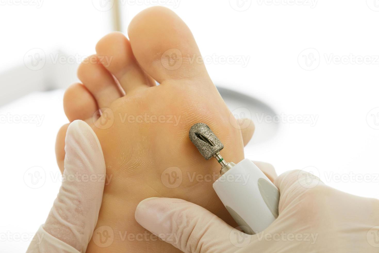 Pedicure master work. Closeup of female feet and hands in gloves with a special machine tool. photo