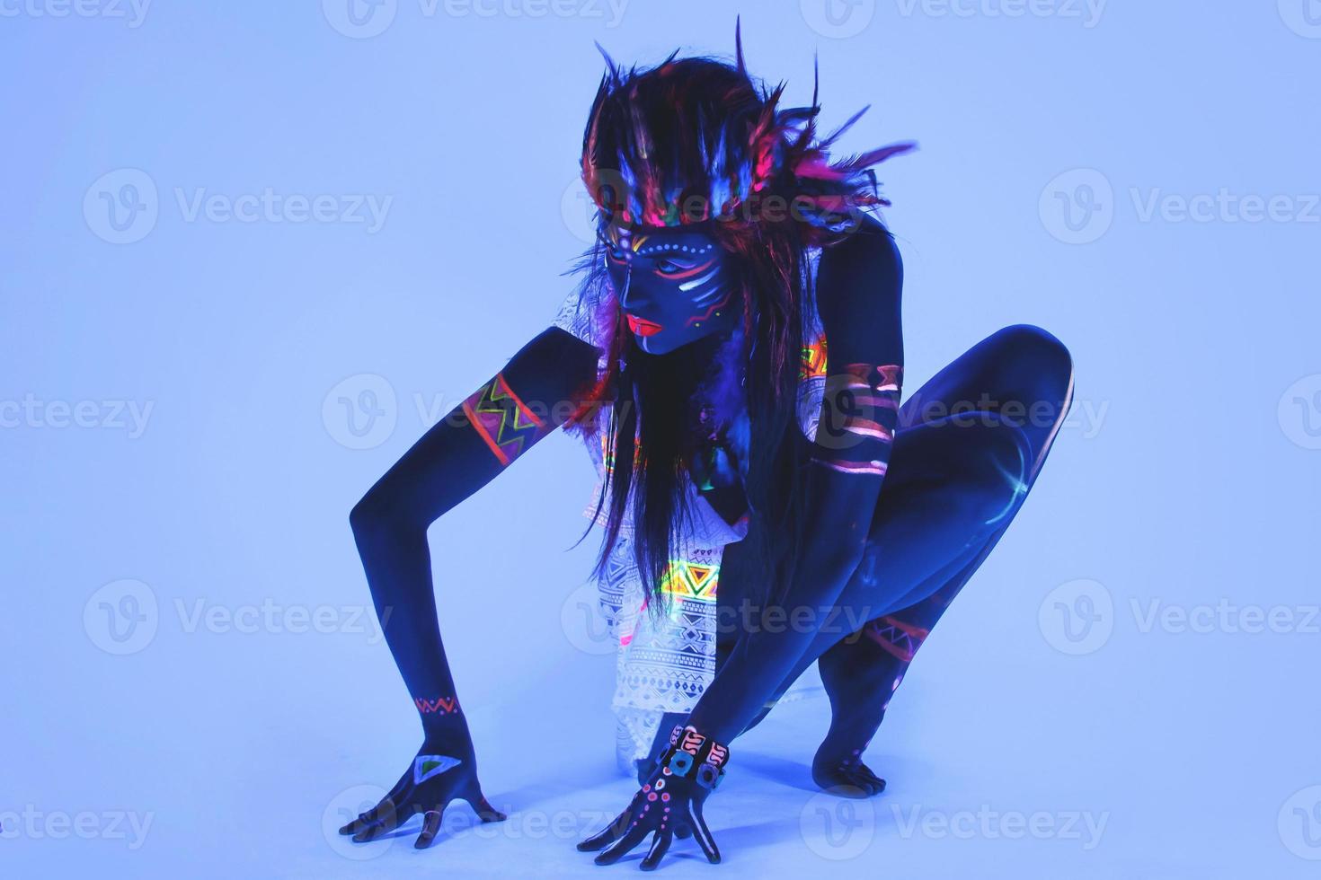 Model in image of Native american with neon makeup, which made of fluorescent paint in ultraviolet light. photo