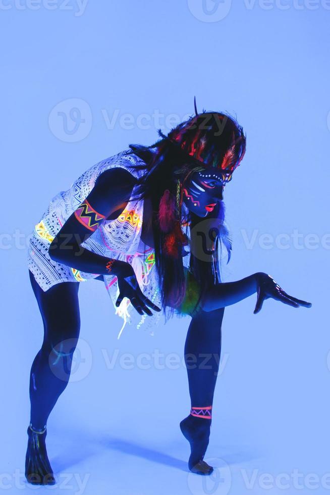 Model in image of Native american with neon makeup, which made of fluorescent paint in ultraviolet light. photo