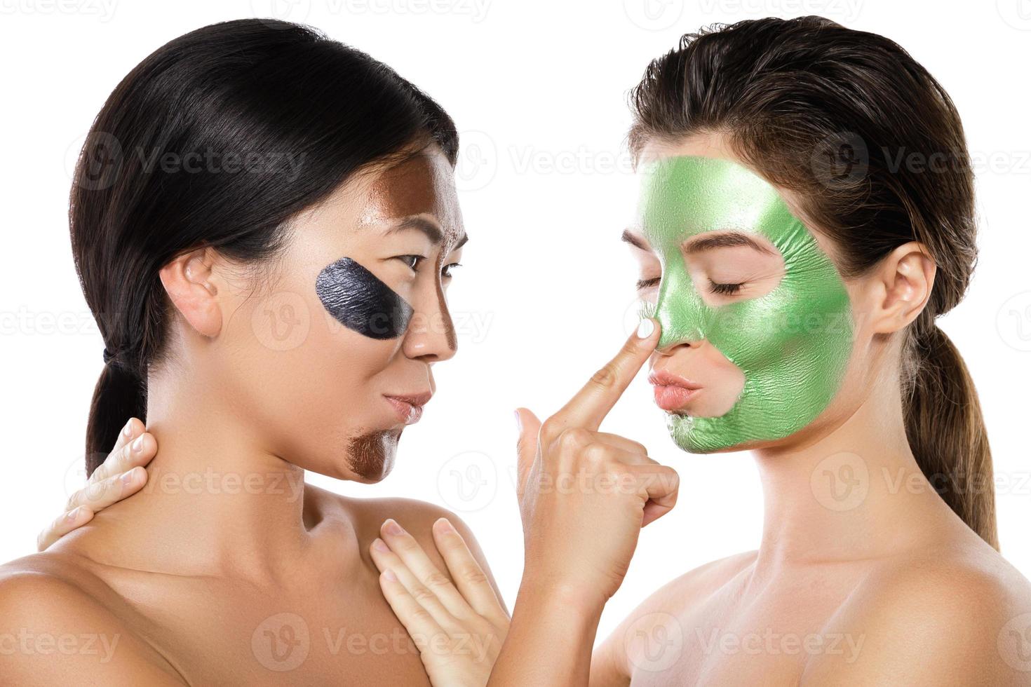 Two beautiful girls with colorful peel-off masks on their faces photo