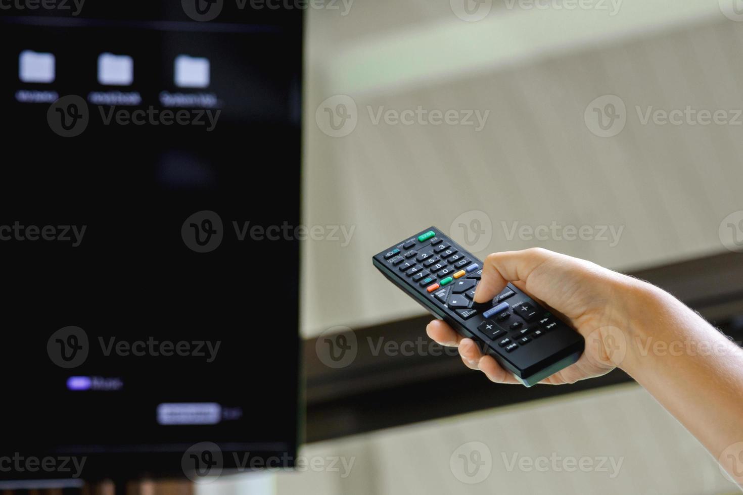 mano femenina con control remoto de tv en la habitación foto