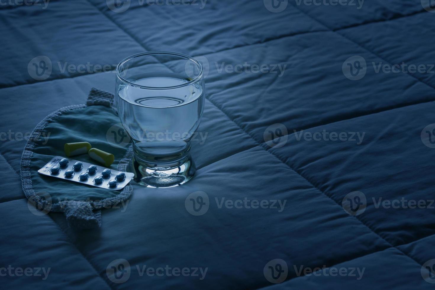 Blister pack of sleeping pills, blindfold and glass of water photo