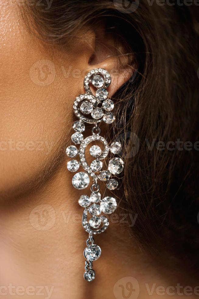 Ear and beautiful big earring with a lot of gemstones photo