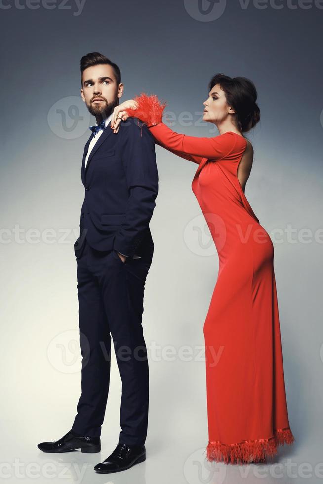 Woman in beautiful red dress and man wearing blue classical suit with bow tie. photo