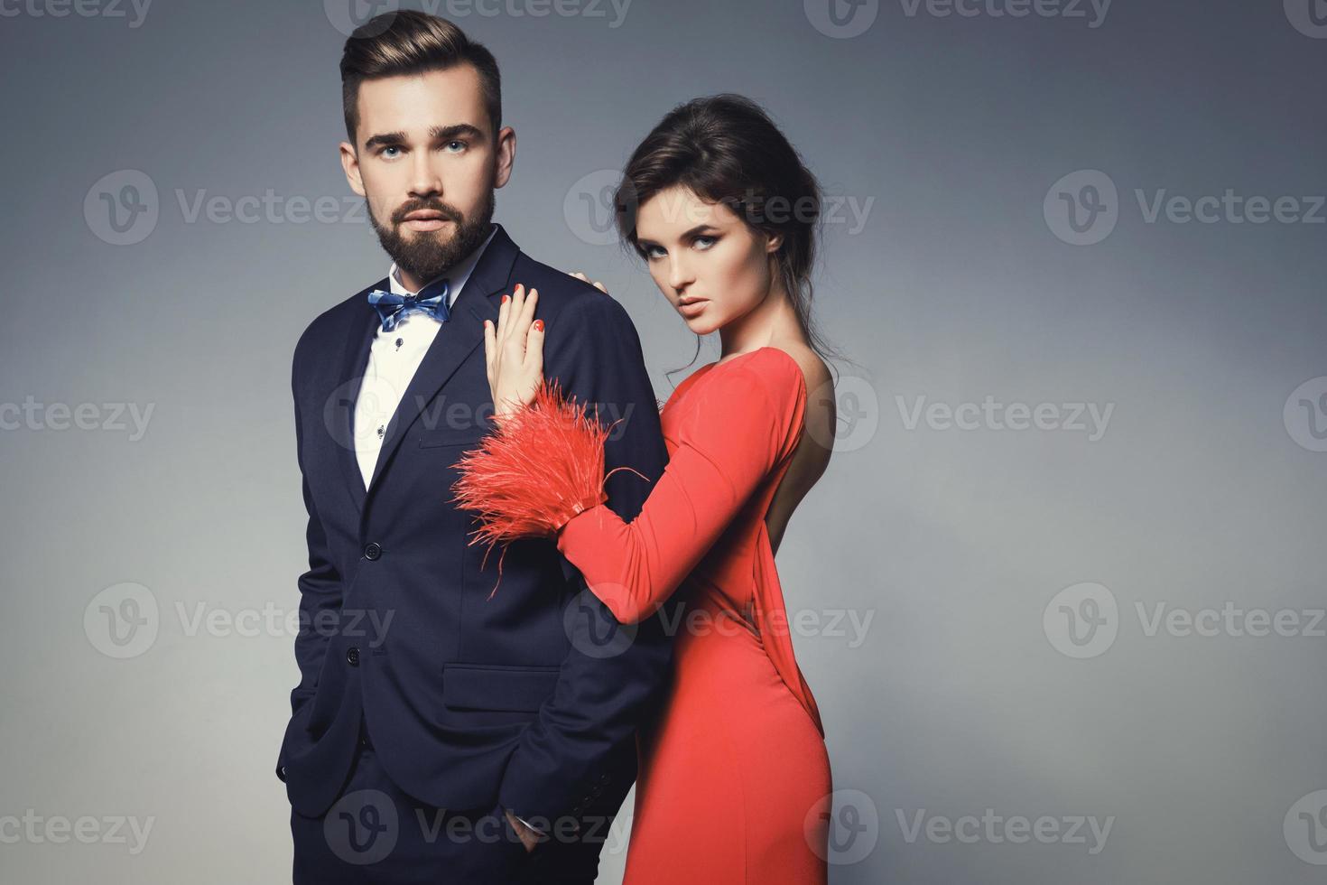 Woman in beautiful red dress and man wearing blue classical suit with bow tie. photo