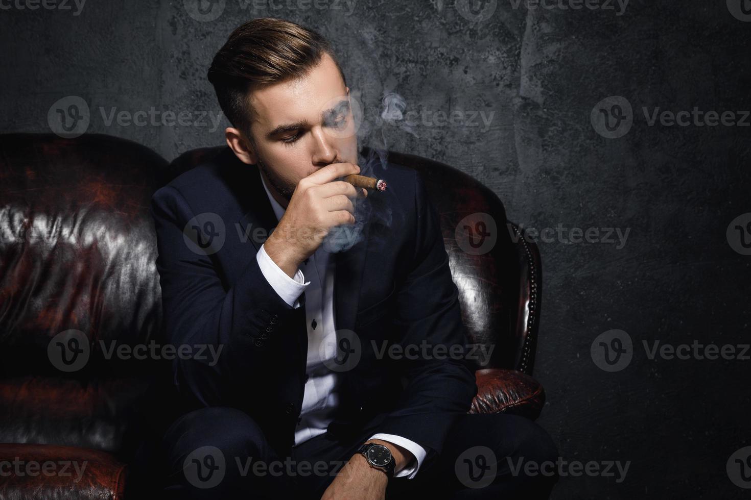 Portrait of handsome rich man is smoking cigar photo