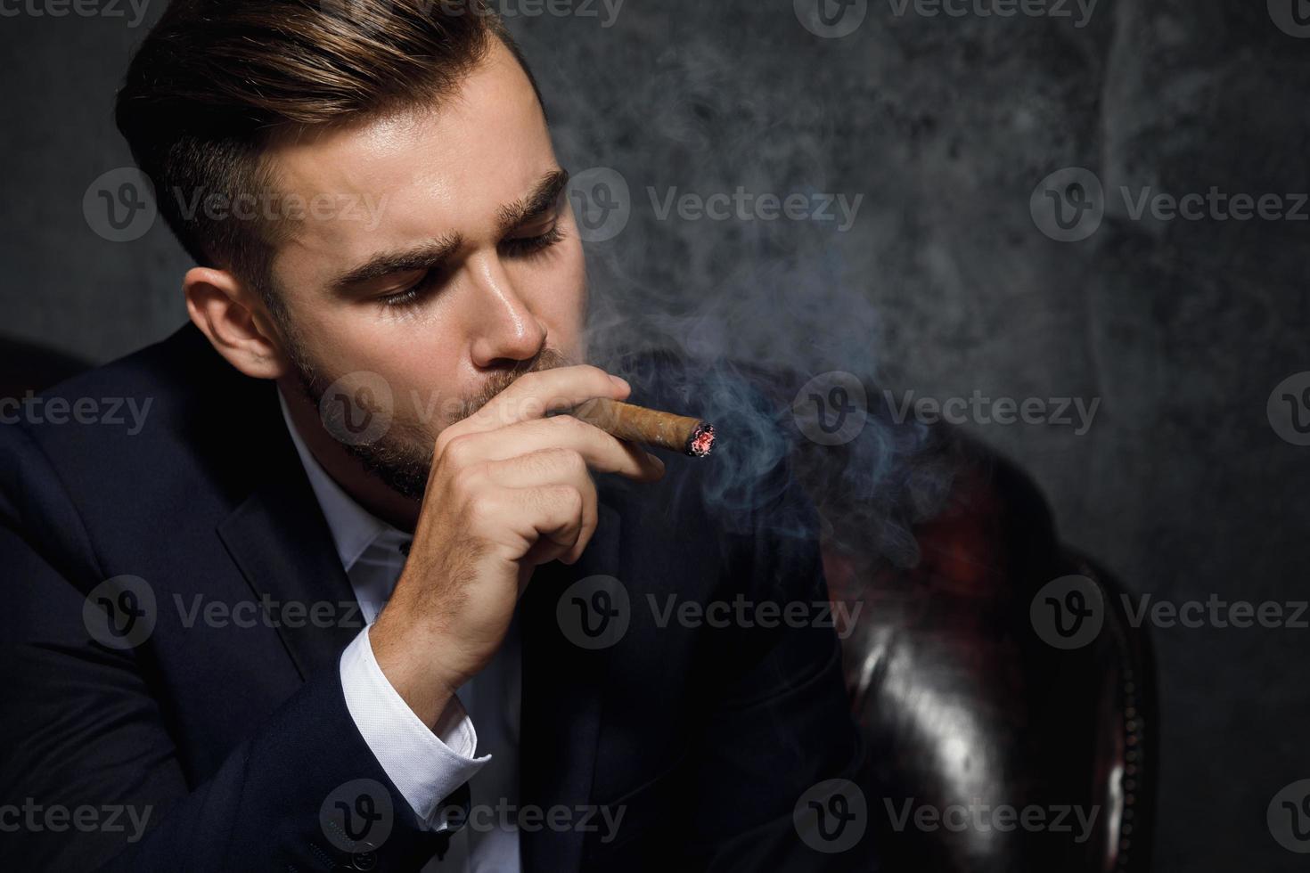 Portrait of handsome rich man is smoking cigar photo