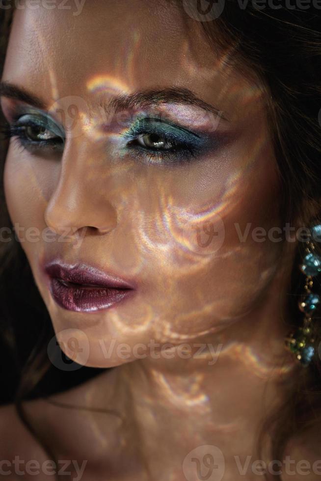 Woman in darkness with a light reflection on her face photo