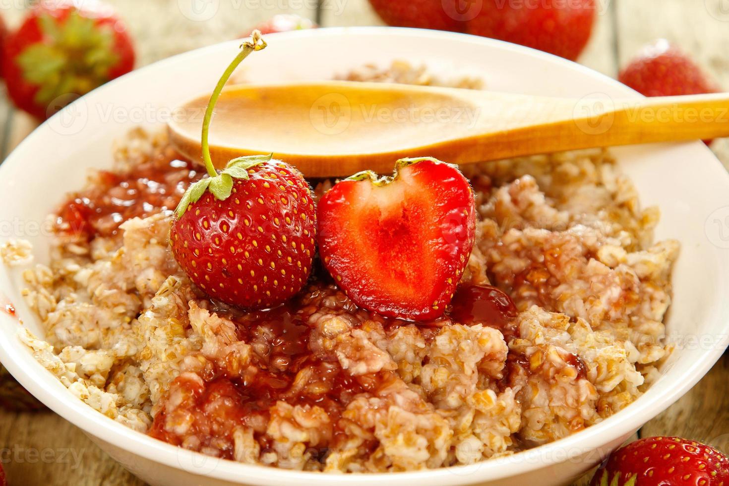 Bowl of cooked oatmeal, berries and strawberry jam photo