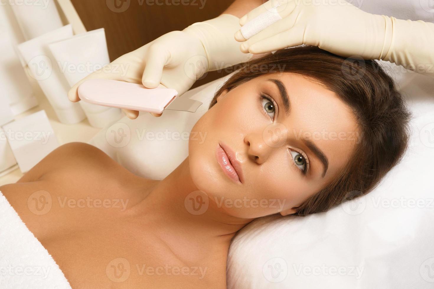 Woman during ultrasonic facial cleansing procedure in clinic photo