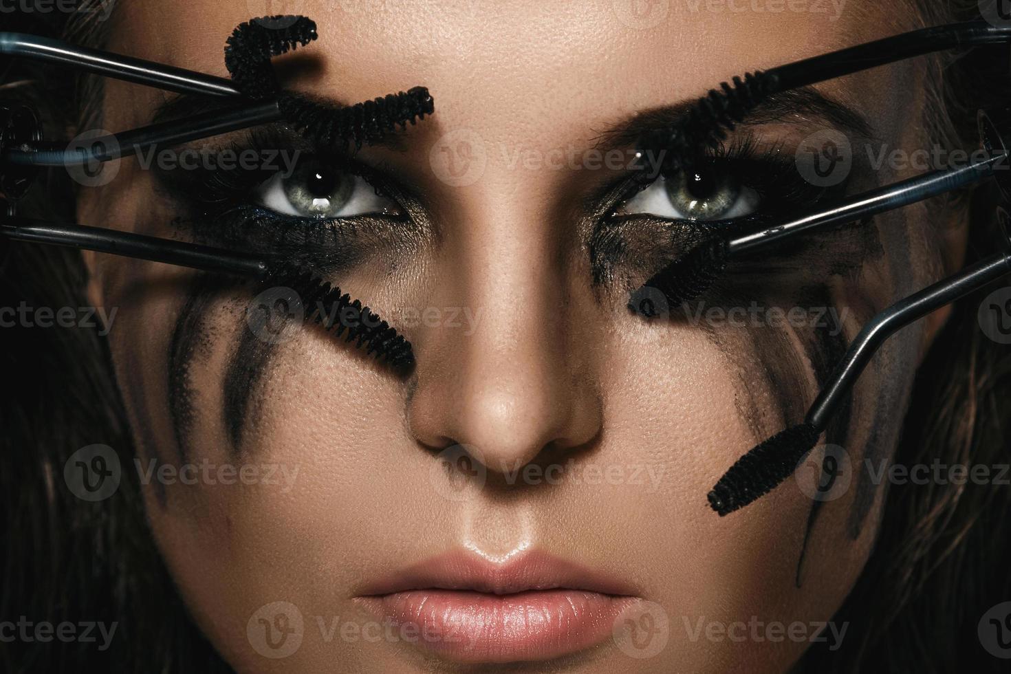 Woman with smudges of makeup on her face and broken mascara brushes photo