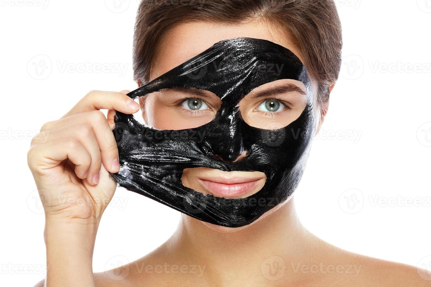 Beautiful woman is removing purifying mask from her face photo