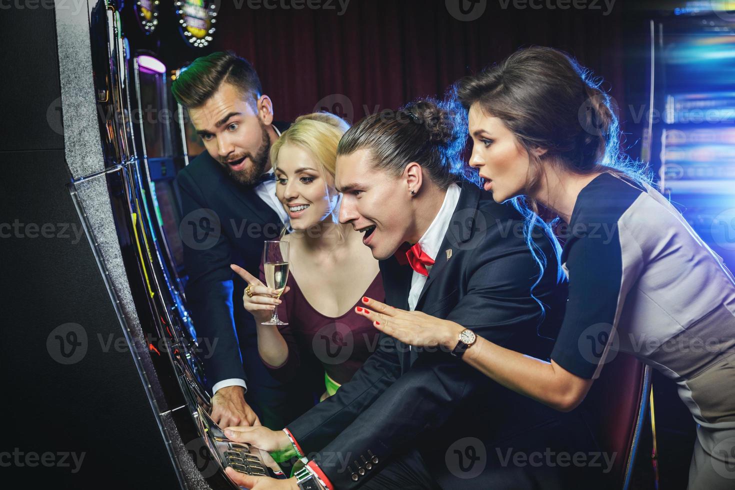 grupo de amigos jugando máquinas tragamonedas en el casino foto