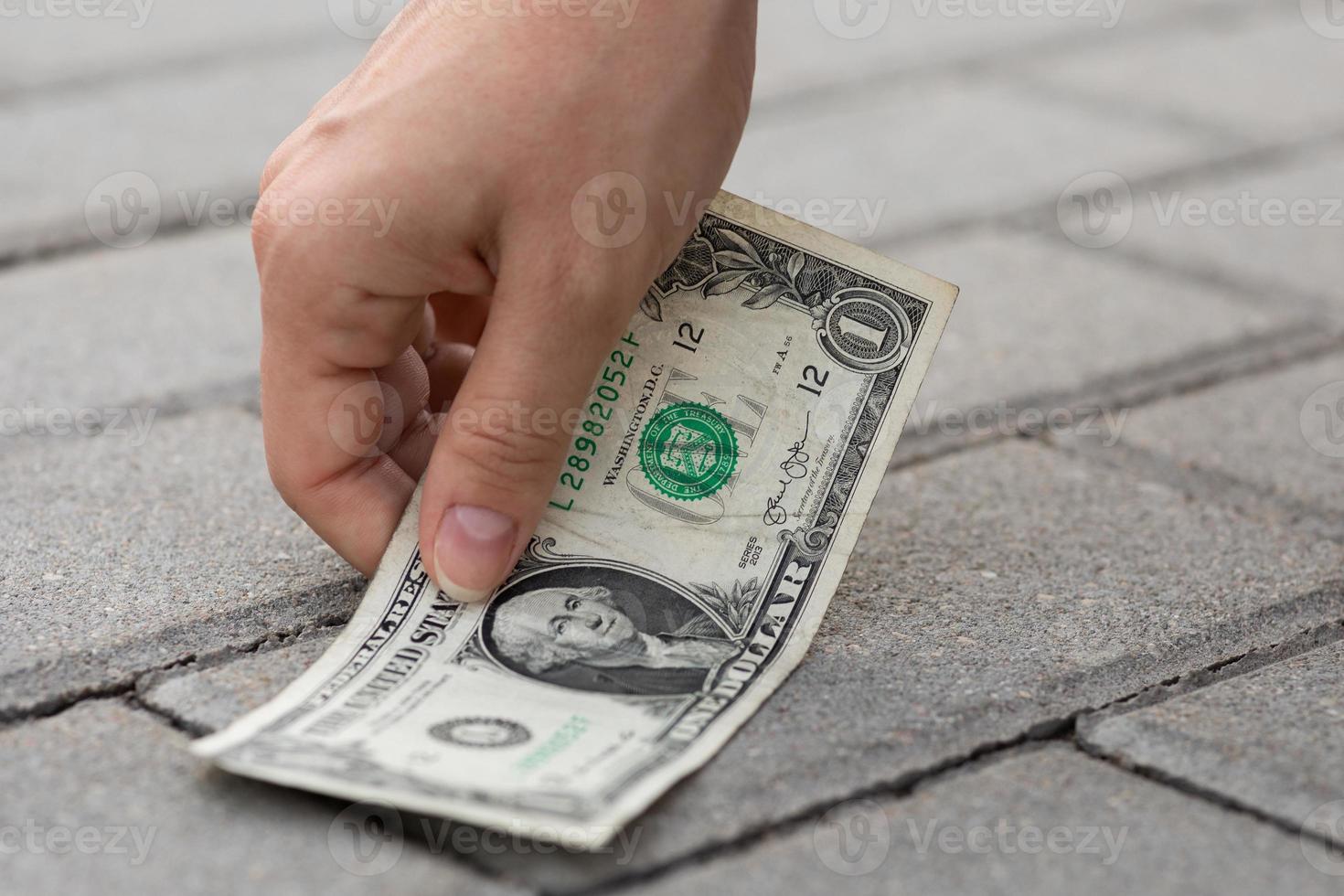 Woman is picking one dollar banknote from the ground. photo