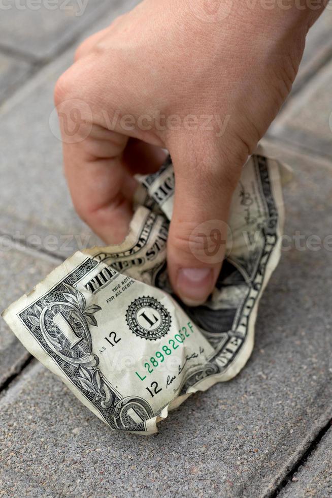 pobre mujer recogiendo un billete de un dólar viejo y arrugado foto